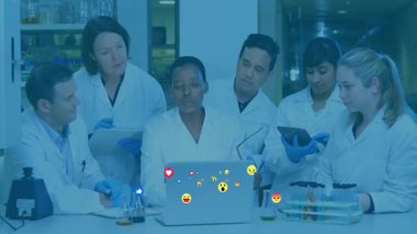 Altı bilim adamı laptop ekranını işaret ediyor ve laboratuvar araştırmaları için yüzen tepkime simgelerini başlatıyorlar. Araştırma, işbirliği, yenilik, laboratuvar, deney, analiz, teknoloji