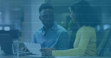 İş arkadaşı finans tablolarını incelerken, kadın da veri örtüşmeleri başlatan belgeye işaret ediyor. İş, kurumsal, analitik, işbirliği, üretkenlik, modern, teknoloji