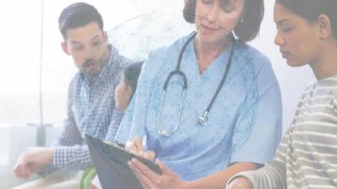 Hemşire notları inceleyip klinikte güncellemeler yazarken sağlık verilerini gösteren animasyon çizelgeleri hazırlıyor. Sağlık, aile, bekleme odası, sağlık, hasta bakımı, belgeler, profesyonel