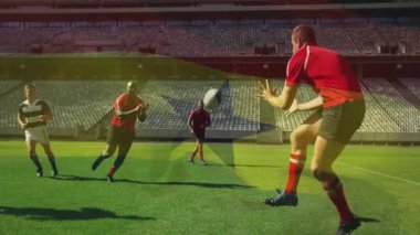 Kırmızı gömlekli ragbi oyuncusu pas alıyor, defans oyuncusu belini zorla indirirken savunmaya hücum ediyor. Sporcular, sporcular, agresif, takım çalışması, aksiyon, yoğunluk, stadyum