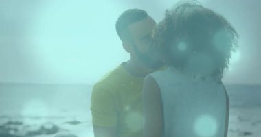 Bokeh küreler sosyal pazarlama için sürüklenirken kayalık kıyı şeridinde bir kadını öpen adam. Romantik, bağlantı, yakınlık, dinginlik, doğal, rüya gibi, sevgi dolu.