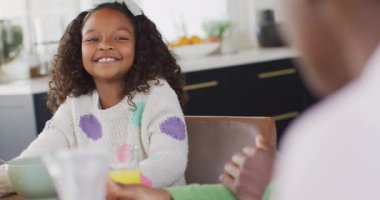 Afro-Amerikan kızının anne babasıyla yemek masasında gülüşünü gösteren bir video. Aile, aile hayatı ve birliktelik kavramı dijital olarak oluşturulmuş video.