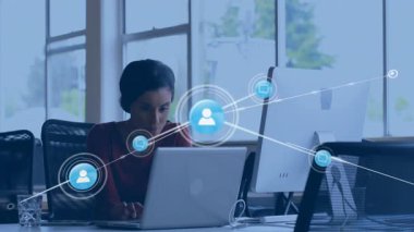 Ofisteki kadın dizüstü bilgisayarda yazıyor, grafikleri titreşerek genişleyen teknoloji ağı simgelerine dönüşüyor. İşbirliği, bağlantı, dijital, teknoloji, iletişim, modern, verimlilik