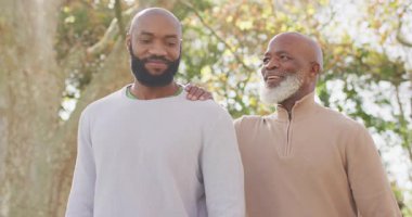 Mutlu Afrika kökenli Amerikalı baba ve yetişkin çocuğun bahçede konuştuğu bir video. Aile, aile hayatı ve birliktelik kavramı dijital olarak oluşturulmuş video.