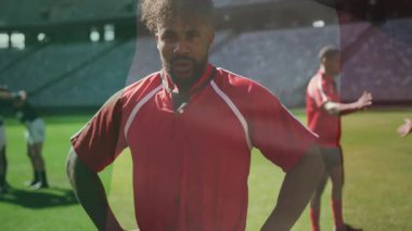 Rugby atletinin çim sahasının ortasında durduğu kamera, takım toplanmasını ve stadyumu gözler önüne seriyor. Sporcu, takım çalışması, spor, yarışma, kararlılık, güç, stadyum