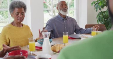 Afro-Amerikan dedelerin yemek masasında aileleriyle el ele dua ederken çekilmiş mutlu bir video. Aile, aile hayatı ve birliktelik kavramı dijital olarak oluşturulmuş video.