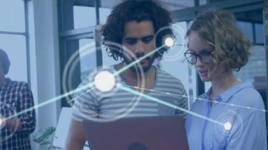 Kadın ve erkek, el bilgisayarı dinledikten sonra dizüstü bilgisayara yaslanıyor, ağ düğümlerinin izini sürüyorlar. Teknoloji, işbirliği, dijital, yenilik, çalışma alanı, bağlantı, geleceksel