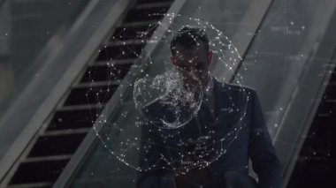 Yürüyen yürüyen merdivenden inen işletme yöneticisi akıllı telefonu kaydırarak dönen veri küresini analiz ediyor. Teknoloji, yenilik, bağlantı, dijital, ağ, kurumsal, fütürist