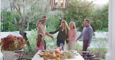 Video of happy caucasian parents, daughter and grandparents taking selfie at outdoor family dinner. Family, domestic life and togetherness concept digitally generated video.