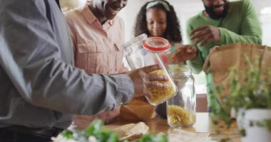 Mutlu Afro-Amerikan ebeveynlerin kız ve büyükbabalarıyla yiyecek paketlerini açarken videosu. Aile, aile hayatı ve birliktelik kavramı dijital olarak oluşturulmuş video.