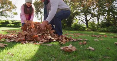 Video of happy caucasian grandfather and granddaughter throwing autumn leaves in sunny garden. Family, domestic life and togetherness concept digitally generated video.