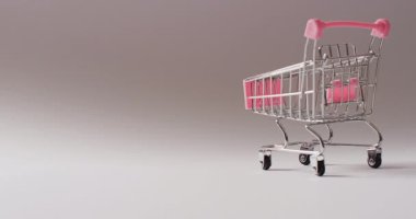 Kusursuz gri arka planda boş pembe alışveriş arabası. Lüks muamele, mevcut, alışveriş, satış ve perakende konsepti dijital olarak oluşturulmuş video.