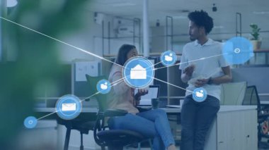 Takım elinde kupa tutuyor ve masaya yaslanıyor. Parlak zarfın ortaya çıktığını ve iş simgelerinin genişlediğini görüyor. İşbirliği, iletişim, bağlantı, dijital, modern, takım çalışması, ofis ortamı