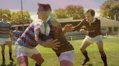 Kırmızı ve siyah formalı oyuncu top kazandıktan sonra koşuyor, topu sağlama alırken ragbi topu sürüyor. Atletik, takım çalışması, rekabet, dinamik, aksiyon, spor, açık hava