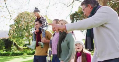 Video of happy caucasian parents walking with son, daughter and grandparents in sunny garden. Family, domestic life and togetherness concept digitally generated video.