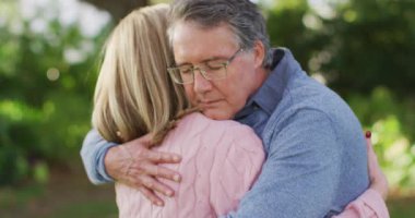 Video of happy caucasian senior husband and wife hugging in garden. Family, love and togetherness concept digitally generated video.
