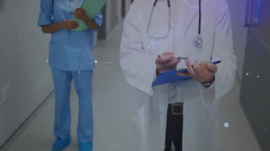 Doktorun pano notları yazdığını, hasta verilerini hemşire gözetimiyle eşleştirdiğini gösteriyor. Hastane, sağlık, sağlık, profesyonellik, teşhis, takım çalışması, dijital