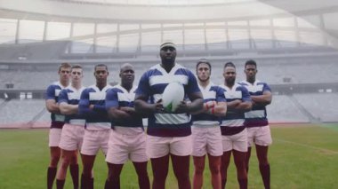 Rugby kaptanı, kamera şeffaf çatı altında yakınlaşırken topu iki kez tutuyor ve kaldırıyor. Sporcular, takım çalışması, sportmenlik, dinamik, rekabetçi, açık hava, kararlılık