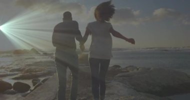 Gün batımında kayalık rıhtıma ayak basan bir çiftin hareketli rota rehberliğinde koşarken görüntüsü. Romantizm, macera, dinginlik, ufuk, doğa, eğlence, manzara