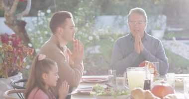 Video of happy caucasian parents, daughter and grandparents saying grace at table before meal. Family, domestic life and togetherness concept digitally generated video.