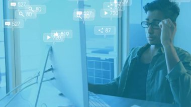 Teknik direktör klavyede yazı yazıyor ve nişan takibi için yüzen sosyal medya istatistikleri yüklüyor. Teknoloji, analitik, çalışma alanı, dijital, profesyonel, kentsel, modern