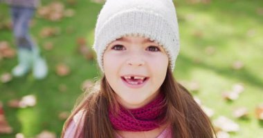 Video of happy caucasian girl in woolly hat and scarf throwing autumn leaves in garden. Childhood, health and happiness concept digitally generated video.
