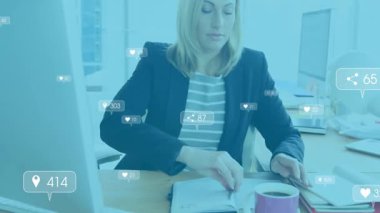 Orta yaşlı bir kadın, sosyal medya simgelerini takip ederken yazıp yazıyor. Profesyonel, çalışma alanı, modern, dijital, iletişim, üretkenlik, analiz