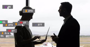 Havaalanındaki dizüstü bilgisayar ölçümlerini inceleyen iş arkadaşları sosyal simgelerde canlanan canlı simgeleri inceliyor. Şirket, modern, teknoloji, iletişim, sunum, büyüme, ağ