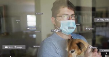 Cerrahi maske takan bir adam çalışma odasında tetikte bekleyen bir köpek ve etrafta beliren teknoloji ikonları. Evcil hayvan, ev, teknoloji, iletişim, sağlık, konfor, modern