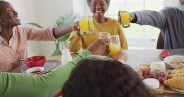 Afro-Amerikan ebeveynlerin, kız ve büyükbabaların yemek masasında kadeh kaldırışlarının videosu. Aile, aile hayatı ve birliktelik kavramı dijital olarak oluşturulmuş video.