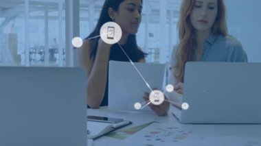 Kağıtları inceleyen kadın iş arkadaşları, ikon ortaya çıktıktan sonra telefon müzik ikonlarını birbirine bağlayan teknoloji ağları kuruyorlar. İşbirliği, ağ oluşturma, dijital, teknoloji, iletişim, takım çalışması, modern