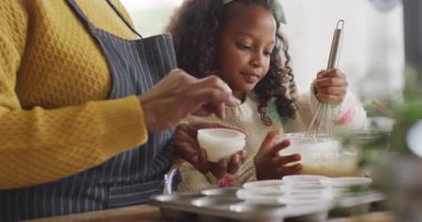 Afro-Amerikan torununun büyükannesiyle mutfakta yemek pişirirken videosu. Aile, aile hayatı ve birliktelik kavramı dijital olarak oluşturulmuş video.