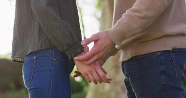 Video of happy caucasian husband and wife holding hands and touching heads in garden. Family, love and togetherness concept digitally generated video.
