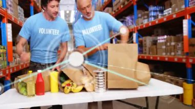 İki gönüllü, hayır kurumu için yiyecek paketliyor. Bağış tabelalarını tutan kadın olarak. Gönüllü olmak, hayır işi, bağış, takım çalışması, topluluk, lojistik, insani yardım