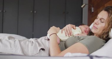 Yeni doğmuş bir bebekle yatakta uyuyan mutlu bir beyaz annenin videosu. annelik, ebeveyn sevgisi ve yeni doğan bebek konseptiyle ilgilenmek dijital olarak üretilmiş video.