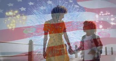 Tahta kaldırımda yürüyen kadın ve oğul pazarlama için bayrak çizgileri ve havai fişekler taşıyor. Kutlama, aile, birliktelik, vatanseverlik, açık hava, eğlence, şenlik