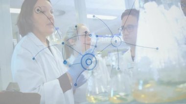 Üst düzey bilim adamı laboratuvar dijital ağının ardından pipeti kaldırıyor ve veri akışını gösteren mataraların üzerinde kayboluyor. Araştırma, yenilik, teknoloji, kimya, işbirliği, bilimsel, fütürist