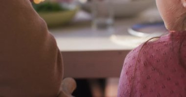 Video of happy caucasian father and daughter holding hands and saying grace at table before meal. Family, domestic life and togetherness concept digitally generated video.