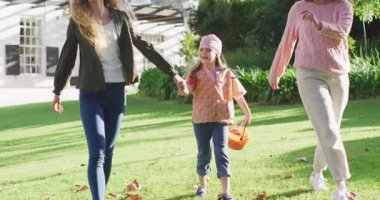 Video of happy caucasian mother and daughter walking with grandmother to trick or treat at halloween. Family, domestic life and togetherness concept digitally generated video.