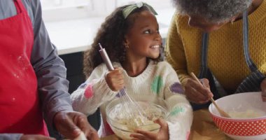 Afrika kökenli mutlu bir Amerikalı torunun büyükannesi ve büyükbabasıyla mutfakta yemek pişirdiği video. Aile, aile hayatı ve birliktelik kavramı dijital olarak oluşturulmuş video.