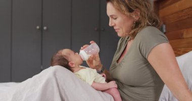 Kafkasyalı mutlu bir annenin yeni doğan bebeği şişeyle beslediği video. annelik, ebeveyn sevgisi ve yeni doğan bebek konseptiyle ilgilenmek dijital olarak üretilmiş video.