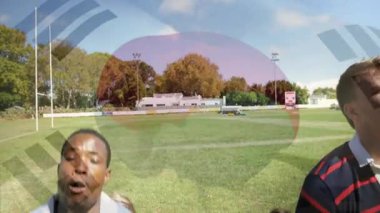 Rugby oyuncusu topa koşuyor ve rakibi logo kaplaması altında kaldırırken top için yarışıyor. Atletizm, rekabet, enerji, takım çalışması, açık hava, dinamik, sportmenlik