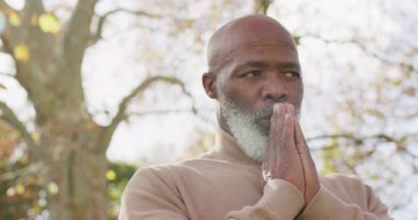 Düşünceli yaşlı Afrikalı Amerikalı adamın bahçede dua ederken el ele tutuşmasının videosu. Emeklilik, inanç, kapsayıcılık, sağlık ve mutluluk konsepti dijital olarak oluşturulmuş video.