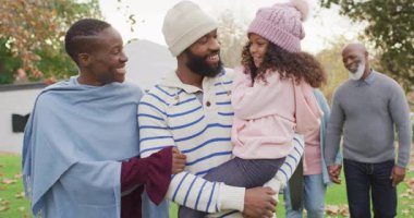 Mutlu Afro-Amerikan ebeveynlerin bahçede yürürken büyük anne ve babalarıyla birlikte kızlarını kucakladıkları bir video. Aile, aile hayatı ve birliktelik kavramı dijital olarak oluşturulmuş video.