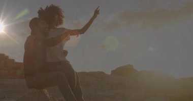 Günbatımında kanyon kenarına yürüyen gezgin çift, sarılıyor, ufuk çizgisini işaret ediyor günbatımı merceğinin parlamasını izliyorlar. Romantizm, macera, siluet, manzara, samimiyet, cennet, bağlantı