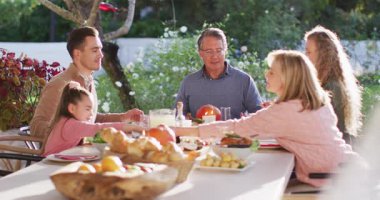 Video of happy caucasian parents, daughter and grandparents saying grace holding hands at table. Family, domestic life and togetherness concept digitally generated video.