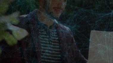 Dizüstü bilgisayara eğilip metni tarayan adam ağ grafiğinin çekilmesine ve teknolojinin çalışmasına neden oluyor. İşbirliği, yenilik, yaratıcılık, açık ofis, modern iletişim, konsantrasyon