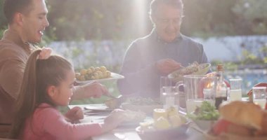 Video of happy caucasian parents, daughter and grandparents serving food at outdoor table. Family, domestic life and togetherness concept digitally generated video.