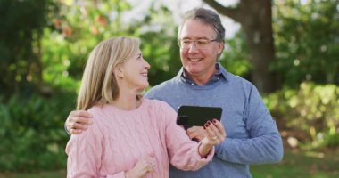 Video of happy caucasian senior husband and wife making video call on smartphone in garden. Family, domestic life and togetherness concept digitally generated video.