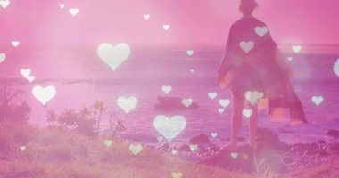 Gün batımında kayalık sahile bakan bir kadın sosyal medya pazarlaması için yükselen kalpler başlatıyor. Romantik, sakin, şiirsel, rüya gibi, sakin, yansıtıcı, sanatsal